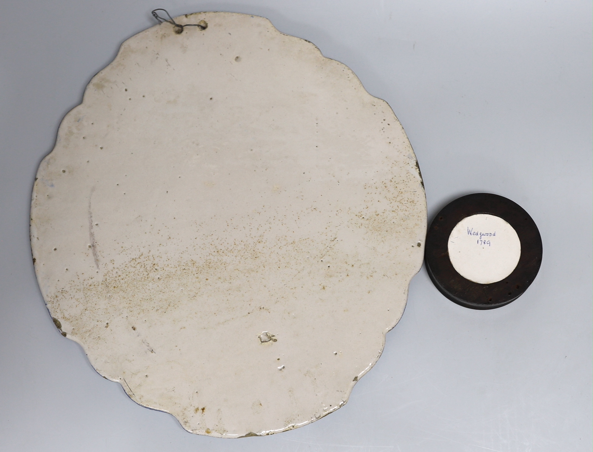 A framed Wedgwood jasperware circular plaque dated 1789 and a delft blue and white example, the largest 37cm high